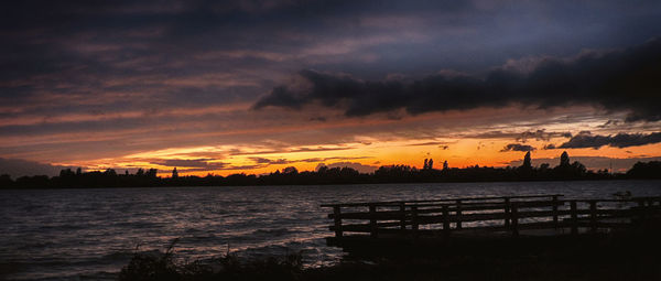 Scenic view of sea against cloudy sky at sunset