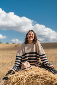 Portrait of smiling woman standing on field against sky