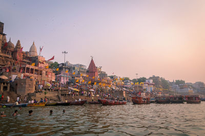 Scenic view of boats in river next to temple against clear sky