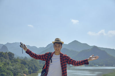 Portrait of young man with arms outstretched standing on mountain