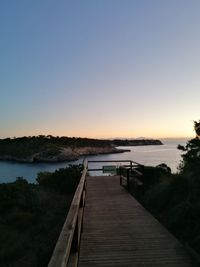 Pier over sea against clear sky during sunset