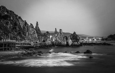 People on rocks by sea against sky