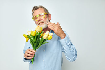 Portrait of young woman holding flower against white background