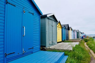 Beach huts by buildings against blue sky