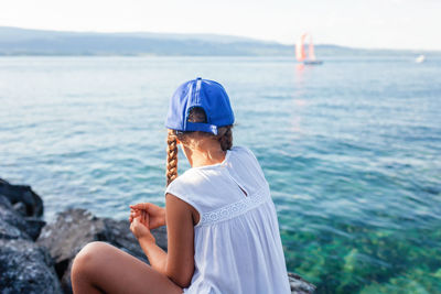 Girl by lake watching sailboats.