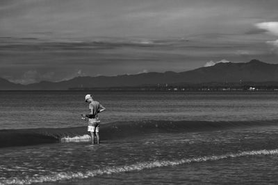 Man standing at beach against sky