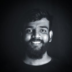 Portrait of young man against black background