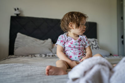 Portrait of cute girl sitting on bed at home