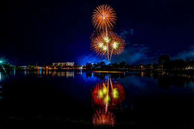 Firework display over lake against sky at night