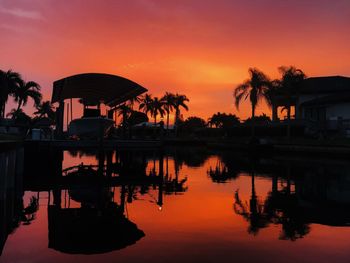 Scenic view of lake by silhouette trees against sky during sunset