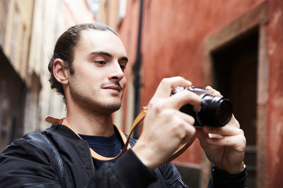 Close-up of smiling young man looking at camera while standing against buildings