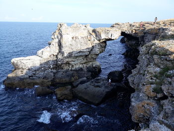 Rocks by sea against sky