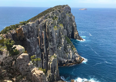 Scenic view of cliff by sea against sky