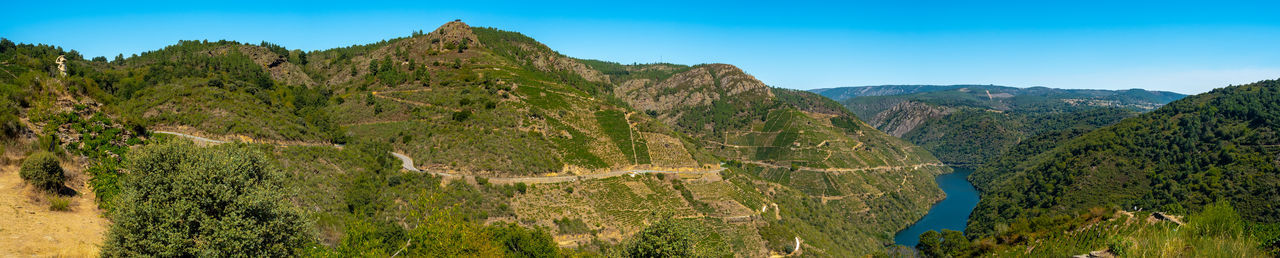 Scenic view of green mountains against blue sky