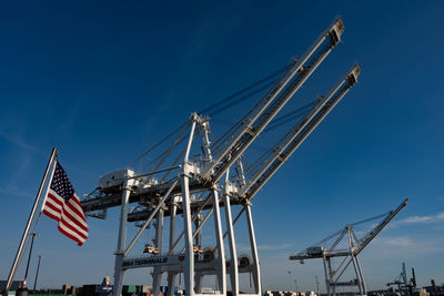 Low angle view of cranes against blue sky