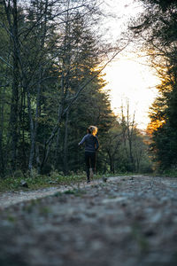 Rear view of woman jogging on footpath in forest