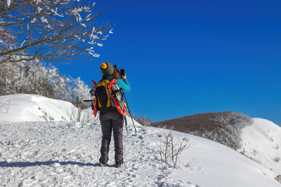 Rear view of woman skiing on snow covered landscape