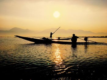 Silhouette man standing in lake against sky during sunset