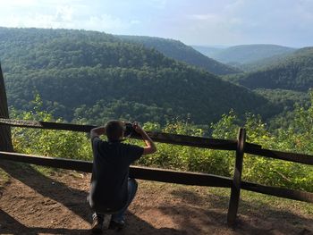 Rear view of man on railing against mountain