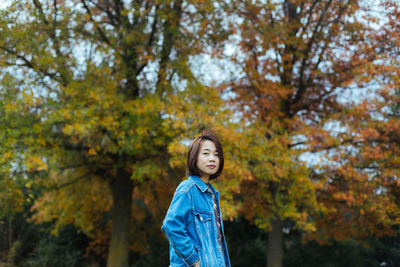 Portrait of mid adult woman standing against autumn trees