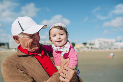 France, la baule, portrait of baby girl on grandfather's arms on the beach