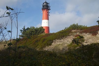 Low angle view of lighthouse by building against sky