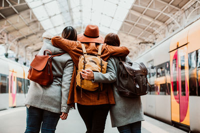 Rear view of people standing on railroad station