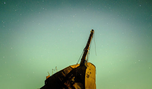 Low angle view of crane at construction site against sky