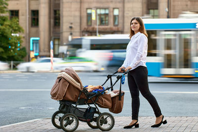 Side view of woman with umbrella on street in city