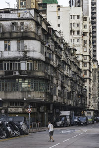 People walking on road by buildings in city