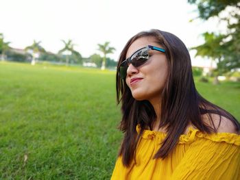 Close-up of smiling woman wearing sunglasses on field