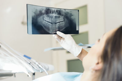 Cropped hand of dentist holding x-ray by female patient