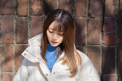 Young woman standing against wall