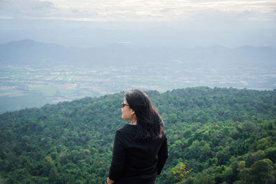 Rear view of woman looking away while standing against mountain landscape
