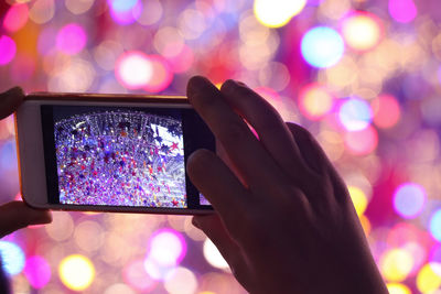 Close-up of hand photographing illuminated decoration