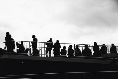 People standing on railing against sky