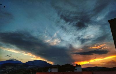 Scenic view of dramatic sky over silhouette mountain