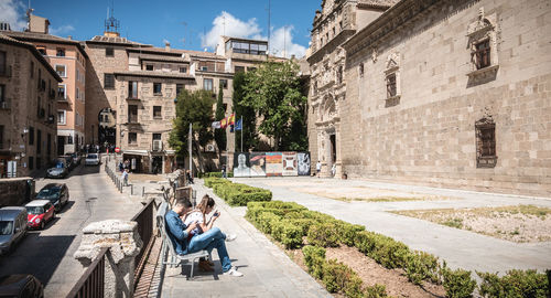 People sitting on street amidst buildings in city