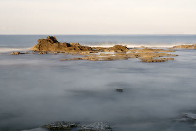 Rock formations in sea against sky