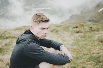 Close-up of man standing by mountain against sky