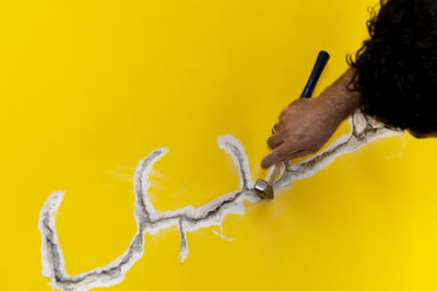 Cropped hand of man scraping wall with hammer