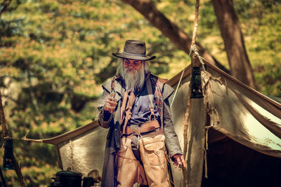 Man holding gun while standing in forest