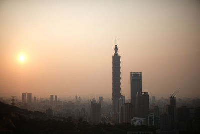 Buildings in city against sky during sunset