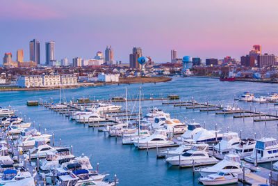 Sailboats moored in harbor against sky in city