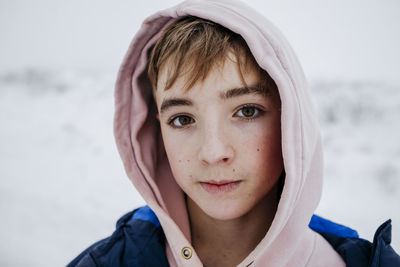 Teenage boy with brown eyes in warm clothing on snow