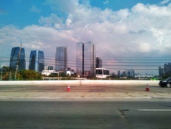 Road by buildings against sky