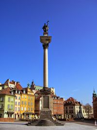 Statue in city against clear blue sky