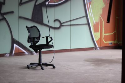 Empty chairs against wall in building