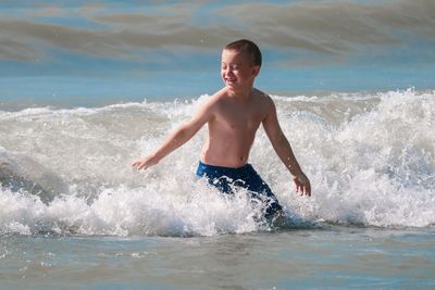 Full length of shirtless boy in sea