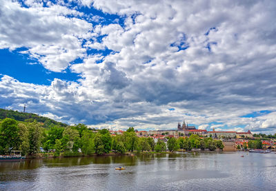 Scenic view of river by buildings against sky